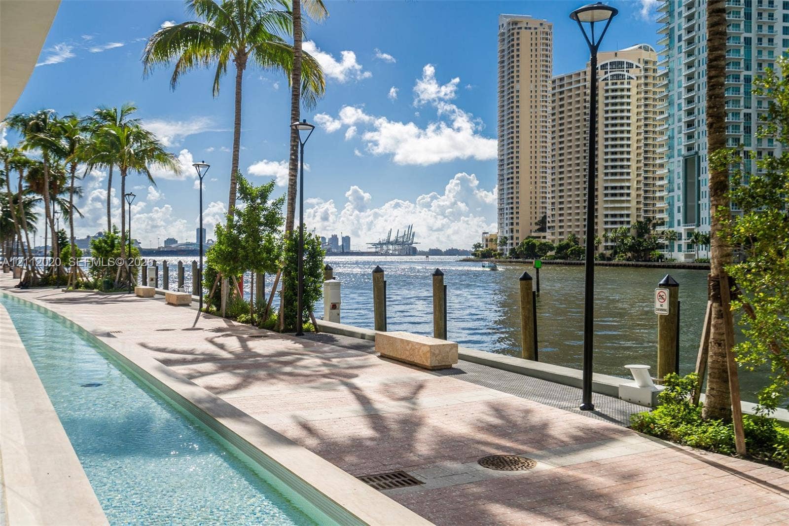 300 Biscayne Blvd Way, #4202, Miami, Miami, FL 33131 Waterfront promenade featuring a tiled walkway, a decorative linear water feature, integrated stone benches, and mature palm trees
