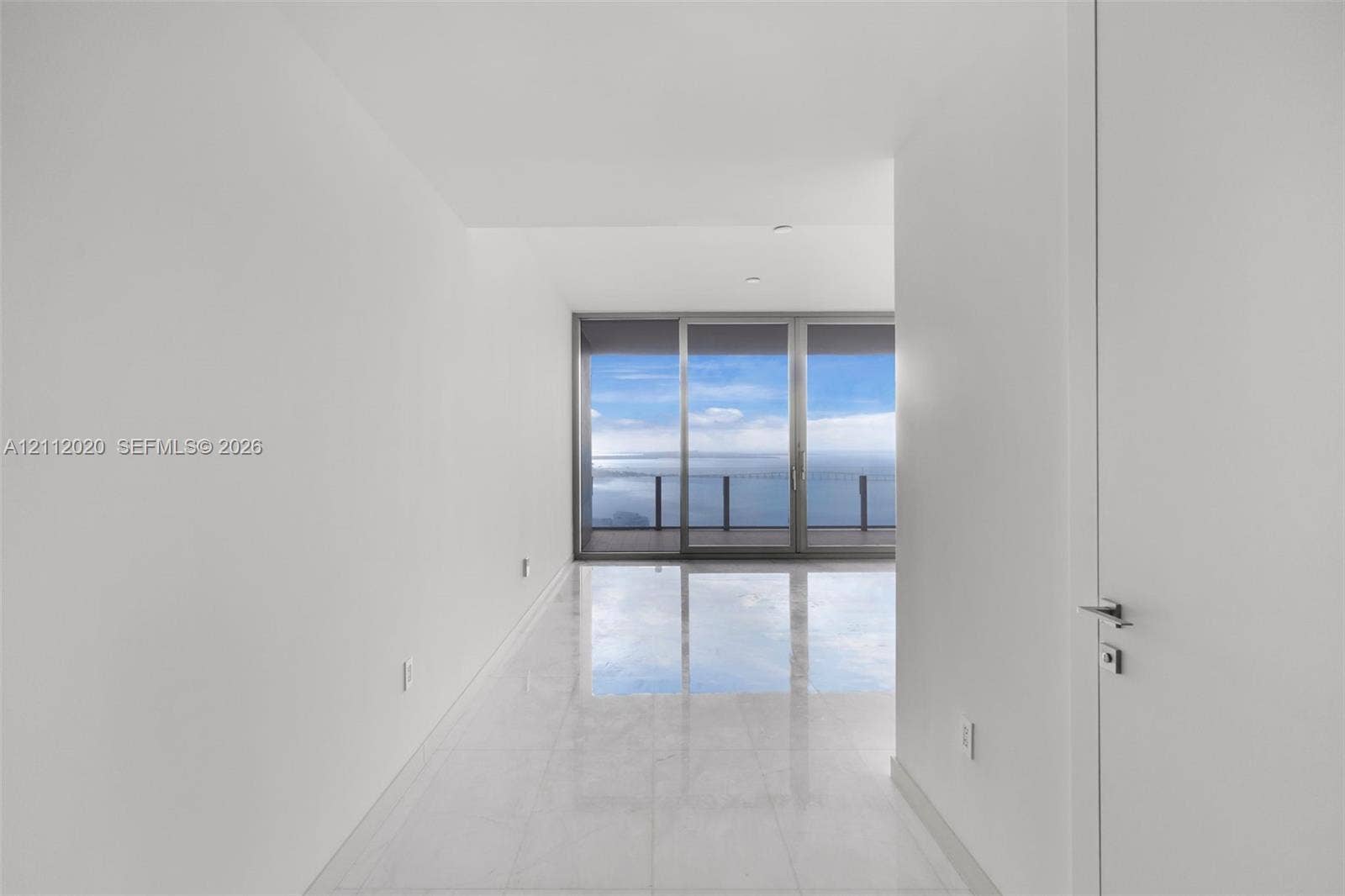 300 Biscayne Blvd Way, #4202, Miami, Miami, FL 33131 Minimalist interior featuring large-format stone flooring, floor-to-ceiling glass sliding doors, and a private balcony with water scenery