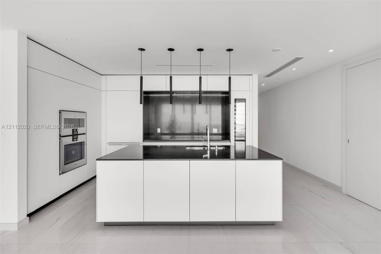 300 Biscayne Blvd Way, #4202, Miami, Miami, FL 33131 Minimalist kitchen featuring flat-panel cabinetry, a central island with a contrasting stone countertop, built-in stainless steel double ovens, a metal backsplash, and suspended cylindrical pendant lighting