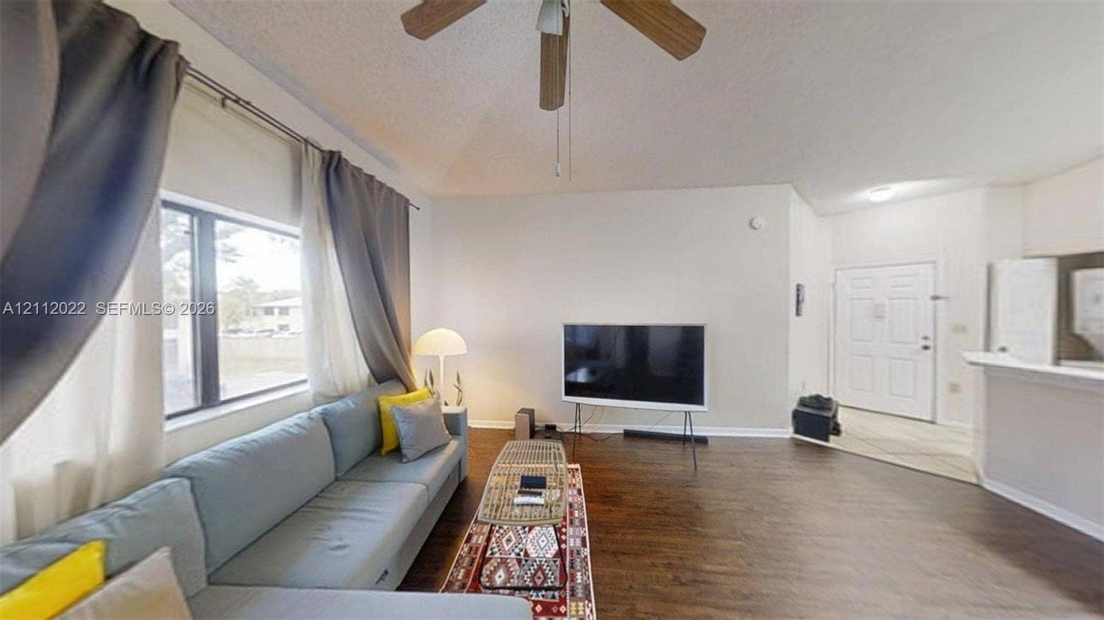 Open-concept living space featuring wood-finish flooring, a ceiling fan, and a neutral color palette