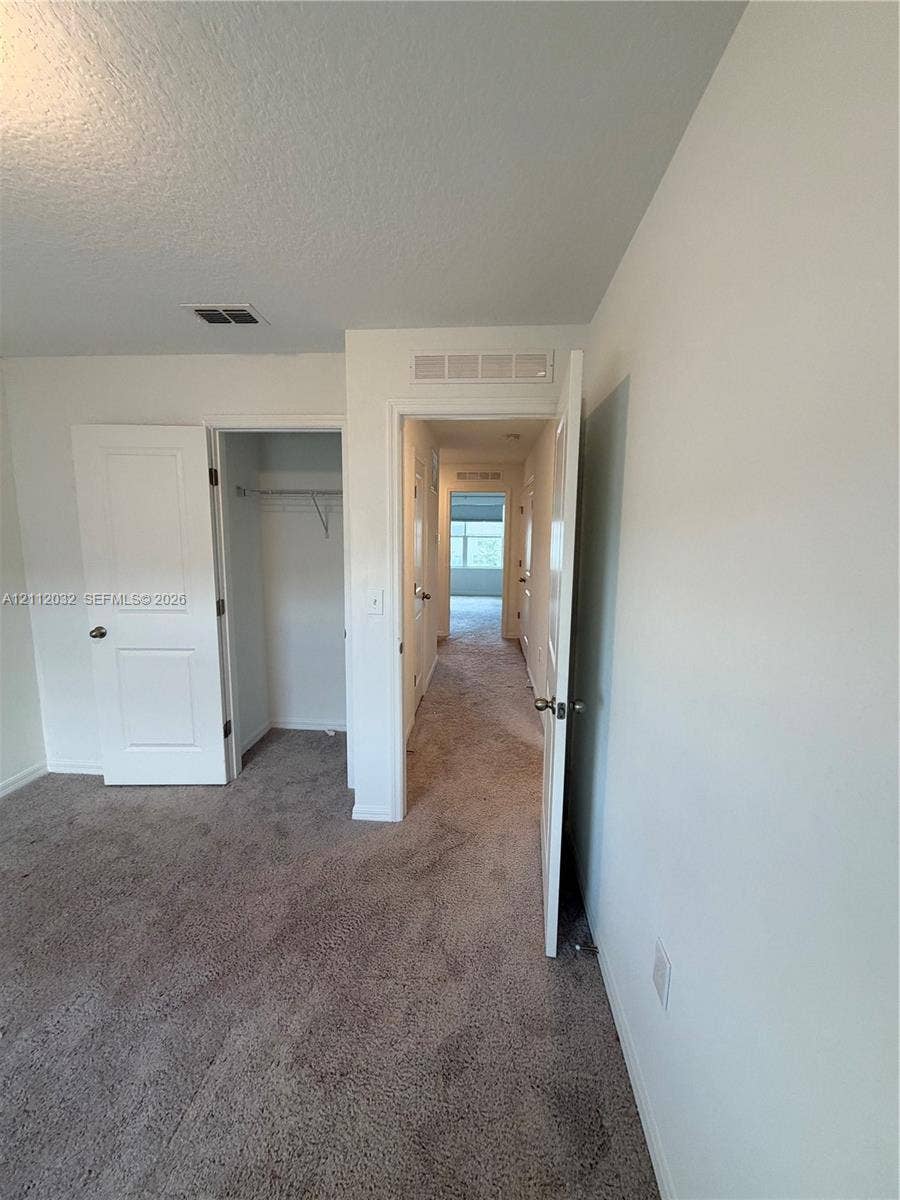 254 Mandovis Street, Davenport, Davenport, FL 33837 Interior space featuring neutral wall tones, wall-to-wall carpeting, and a reach-in closet with integrated shelving