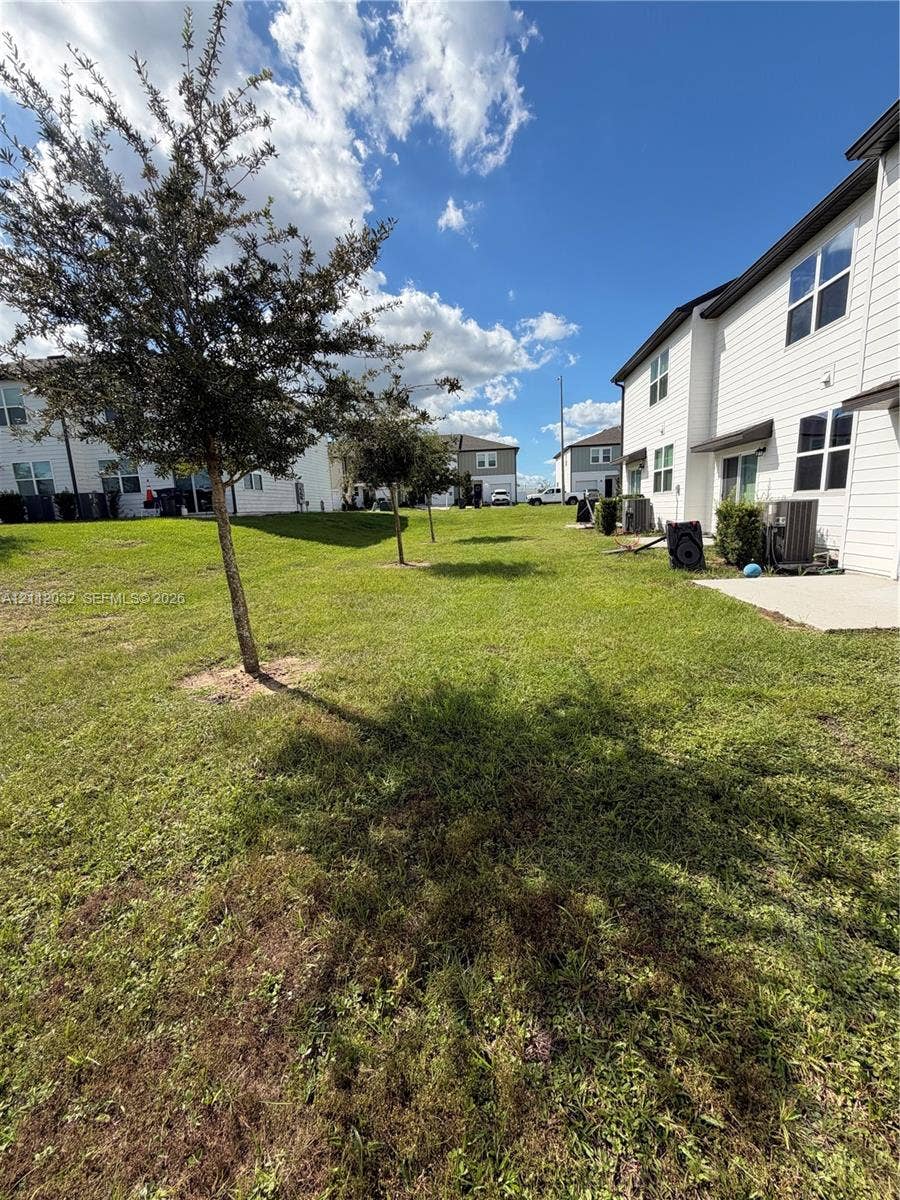 254 Mandovis Street, Davenport, Davenport, FL 33837 Exterior space featuring horizontal siding, a concrete patio, and landscaped lawn with mature trees