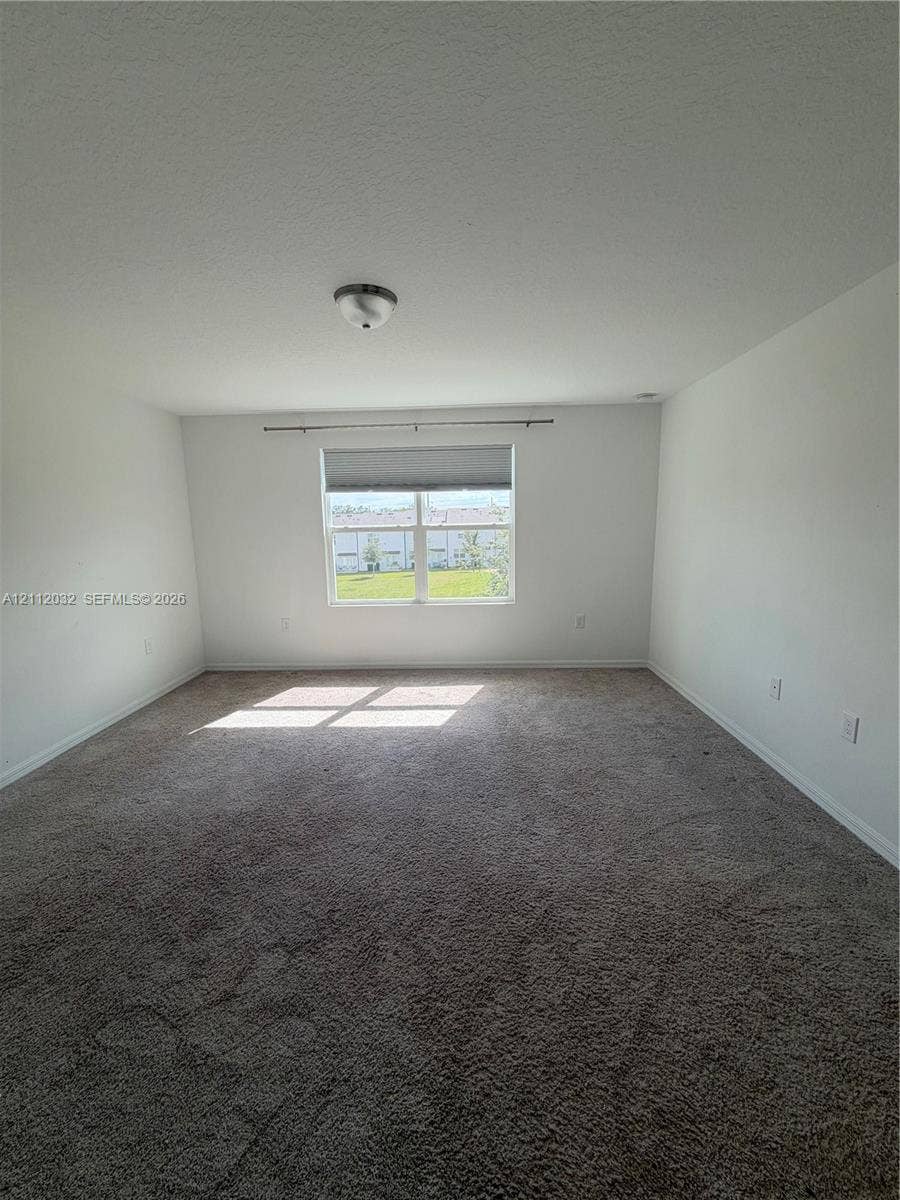 254 Mandovis Street, Davenport, Davenport, FL 33837 Interior space featuring neutral-toned carpeting, a single-pane window with a roller shade, and a flush-mount ceiling light fixture