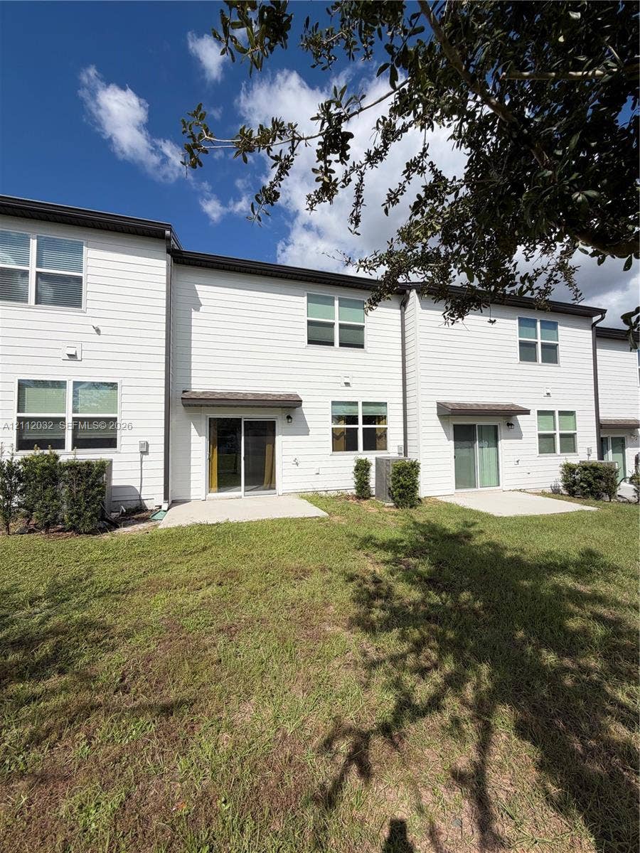 254 Mandovis Street, Davenport, Davenport, FL 33837 Multi-family exterior featuring horizontal siding, concrete rear patios, sliding glass doors, and dual-pane windows