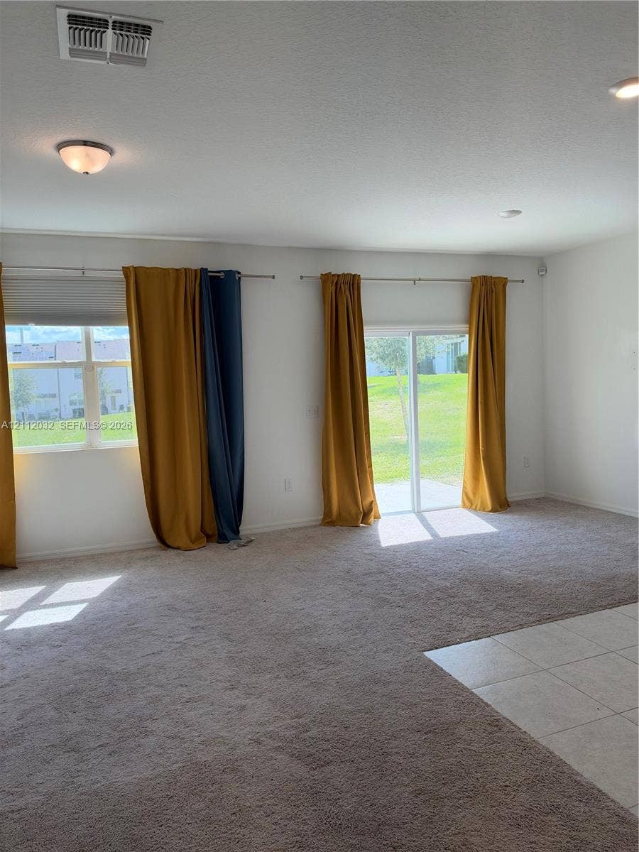 254 Mandovis Street, Davenport, Davenport, FL 33837 Interior space featuring wall-to-wall carpeting, tile flooring, flush-mount lighting fixtures, and a sliding glass door