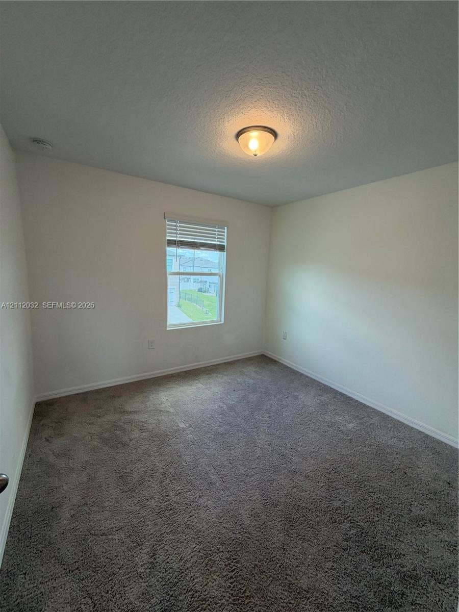 254 Mandovis Street, Davenport, Davenport, FL 33837 Interior room featuring neutral wall paint, plush carpeting, a single-hung window with horizontal blinds, and a central flush-mount ceiling light fixture