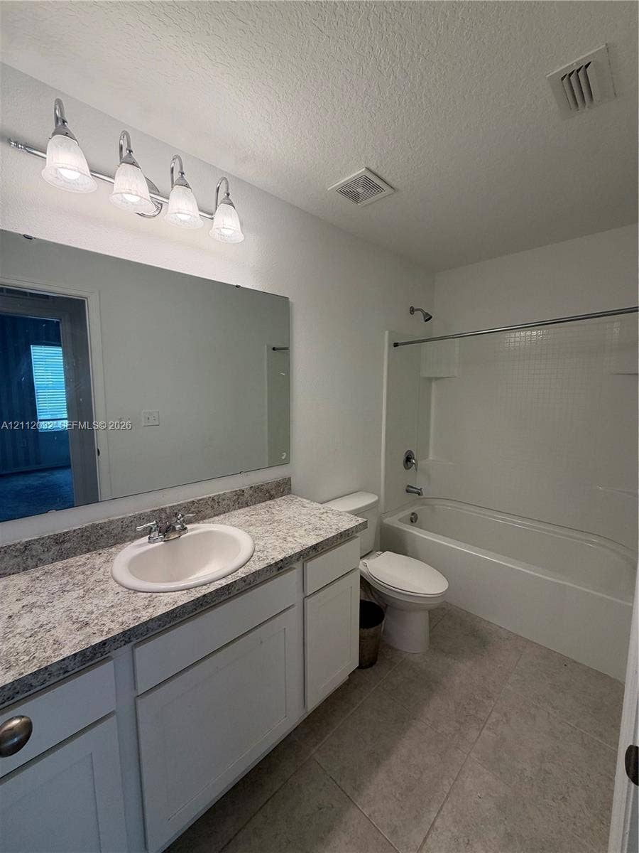254 Mandovis Street, Davenport, Davenport, FL 33837 Bathroom featuring a white vanity with a stone-finish countertop, undermount sink, expansive wall mirror, four-light vanity fixture, and a tub-shower combination with tile surround