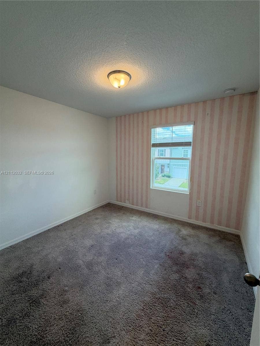 254 Mandovis Street, Davenport, Davenport, FL 33837 Interior room featuring wall-to-wall carpeting, a single-pane window, flush-mount ceiling lighting, and an accent wall with striped wallcovering