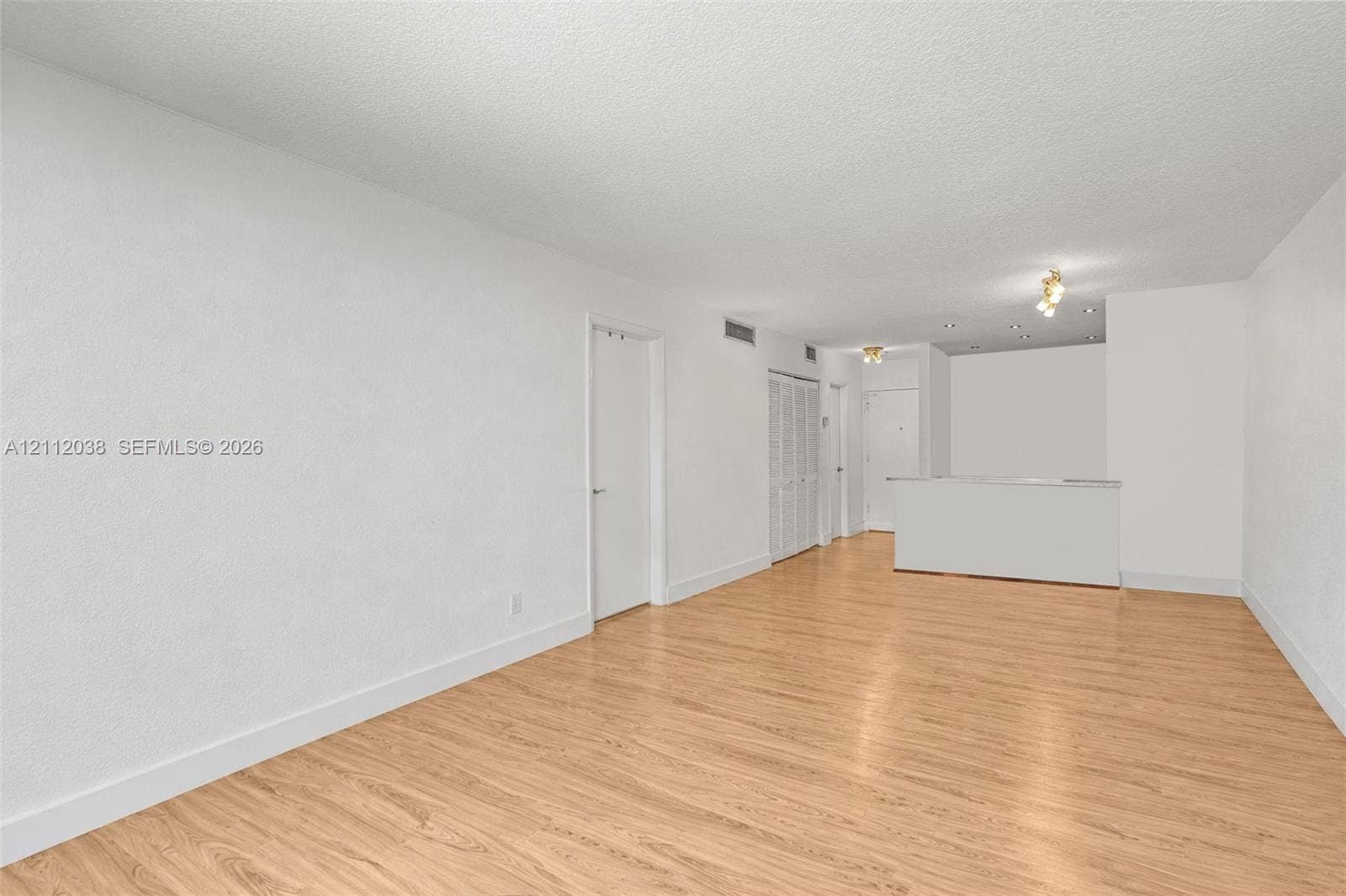 Interior space featuring wood-finish flooring, white walls, built-in cabinetry with louvered doors, and recessed ceiling lighting