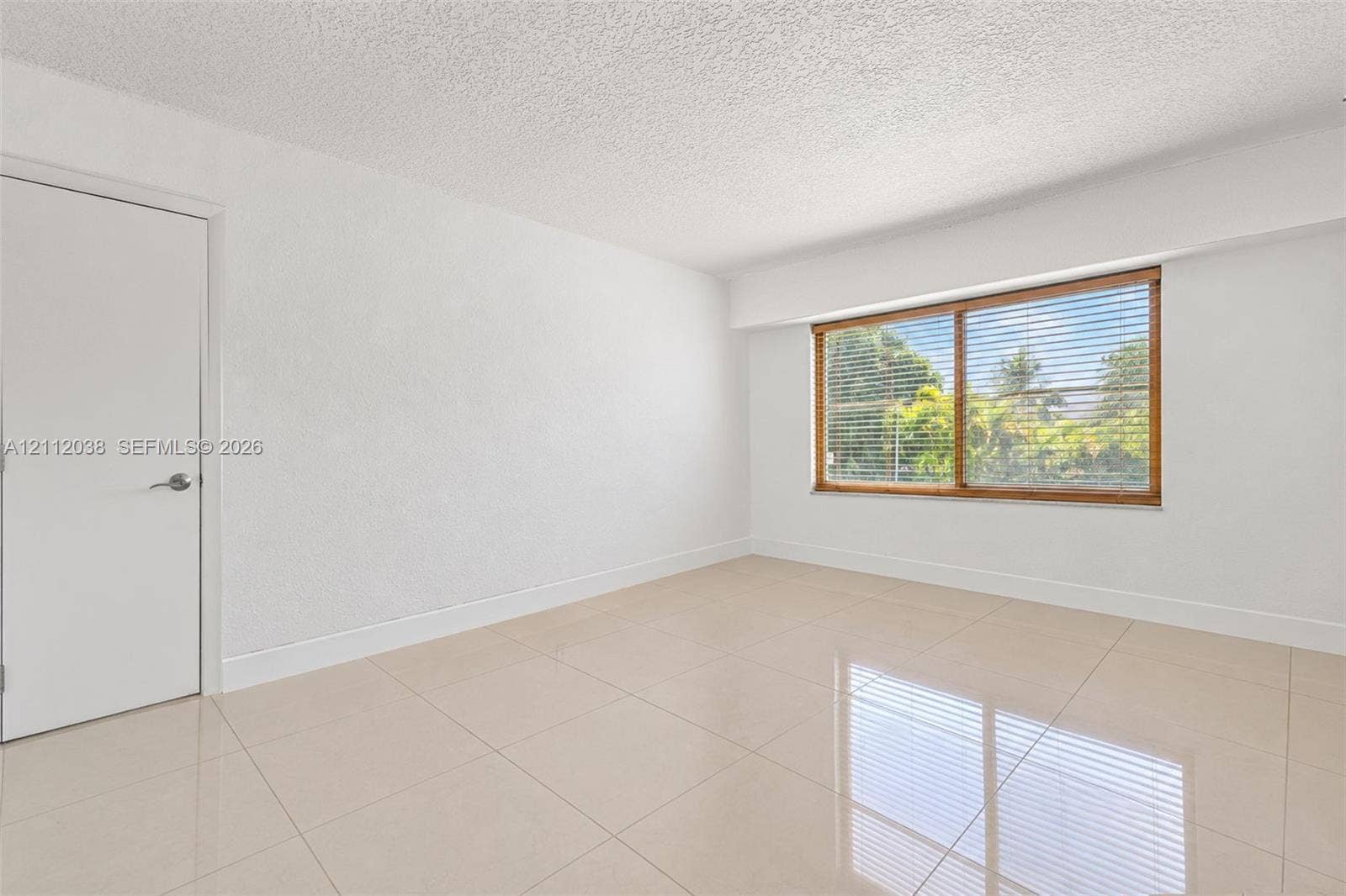 Bright interior space featuring polished tile flooring, smooth wall finishes, and a large window with natural light