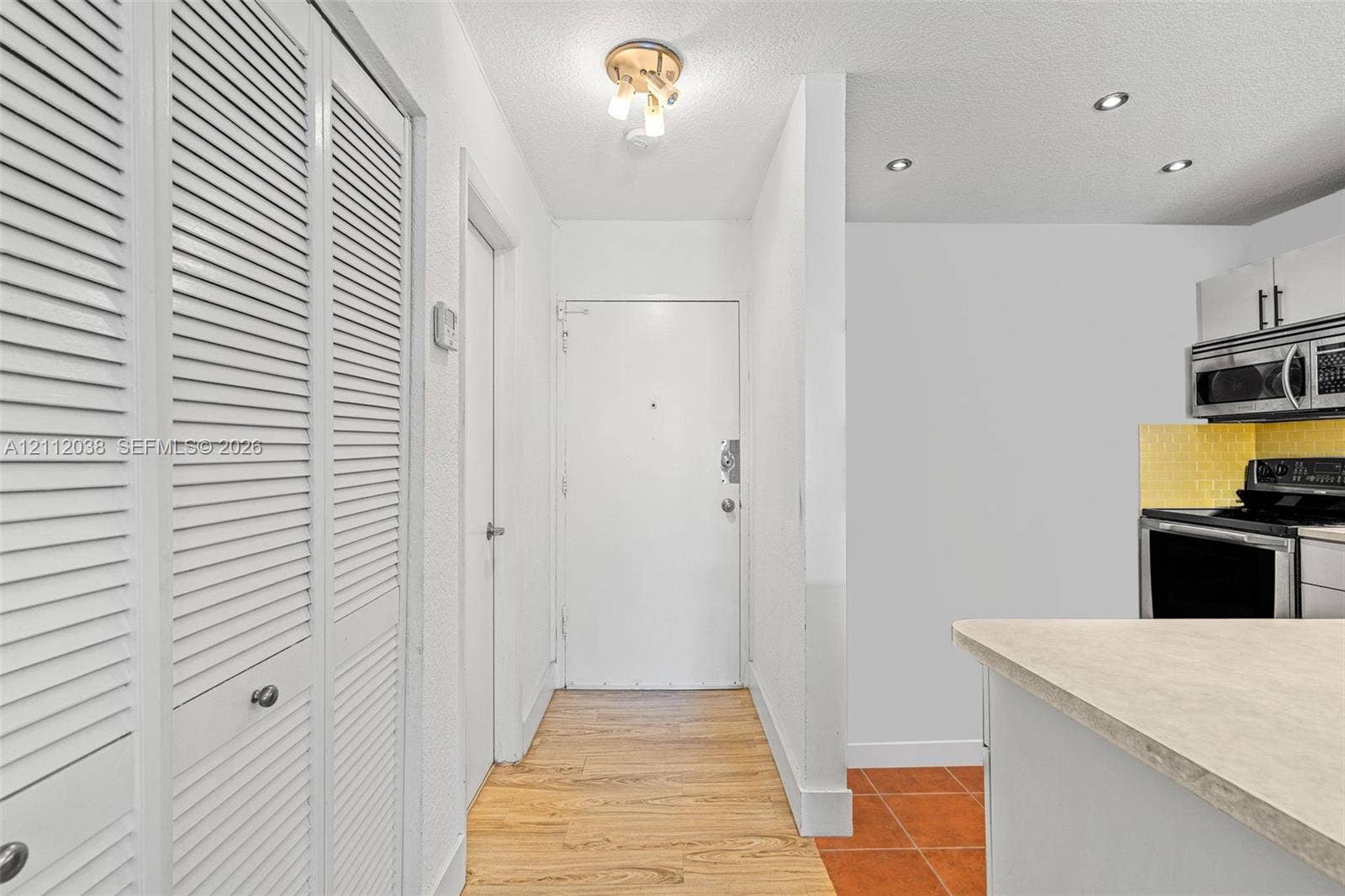 Entrance hall featuring wood-finish flooring, white louvered-door closets, a semi-flush mount light fixture, and recessed lighting