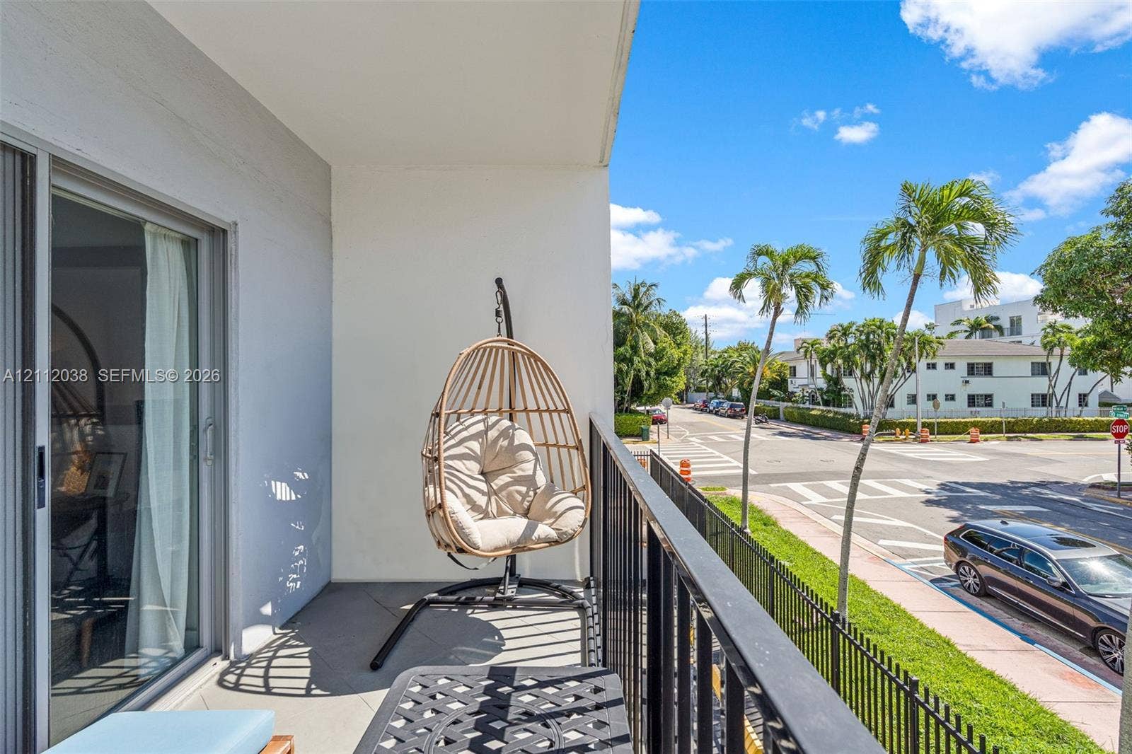 Covered balcony featuring concrete flooring, a black metal railing, and sliding glass doors