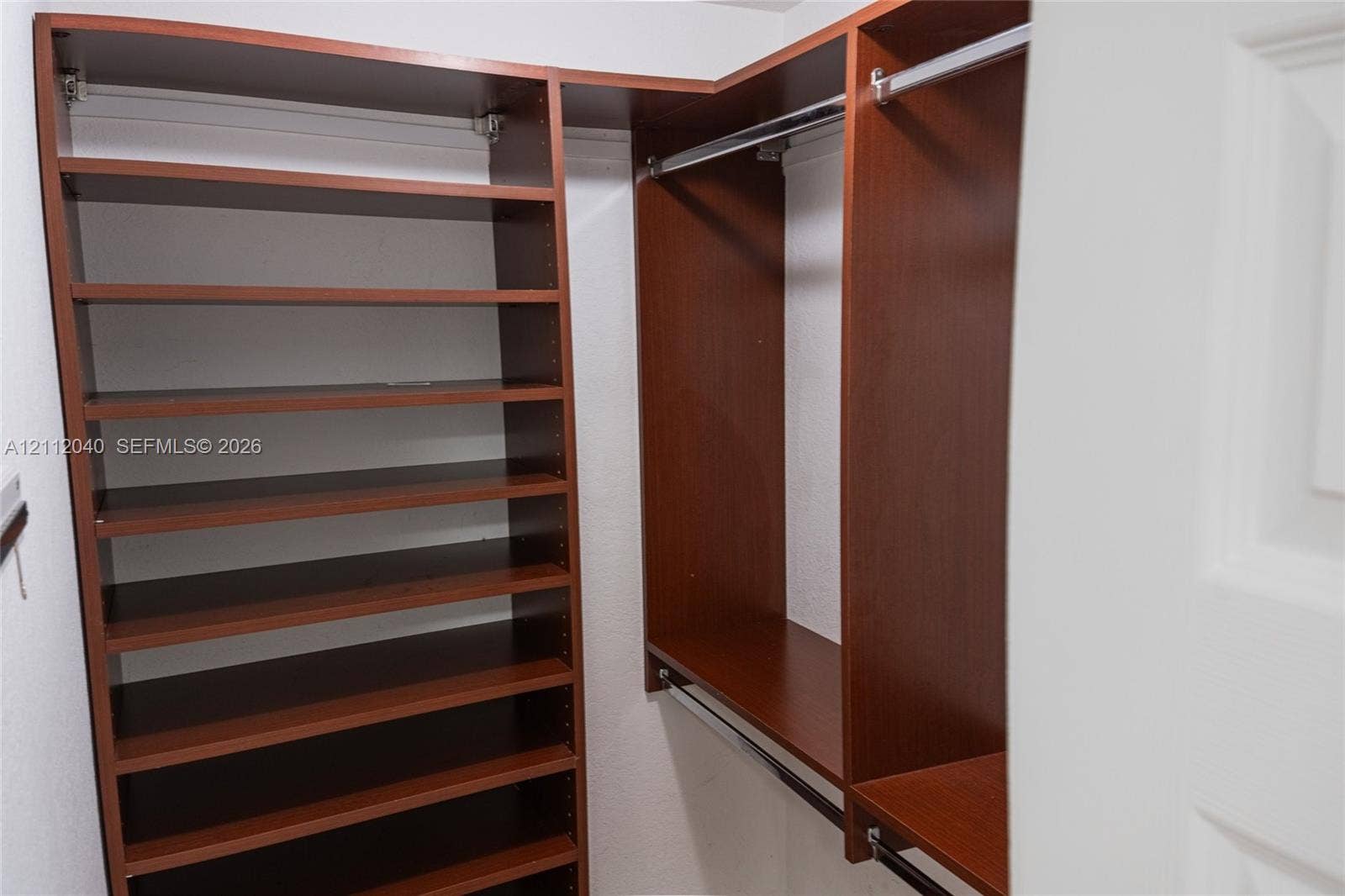 Built-in closet organization system featuring wood-finish cabinetry, adjustable shelving, and integrated metal clothing rods