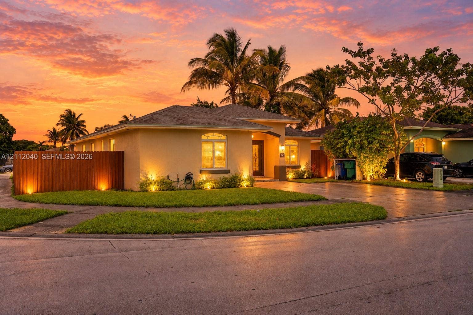 Single-story exterior featuring light-toned stucco siding, an asphalt shingle roof, a paved driveway, and an arched entryway