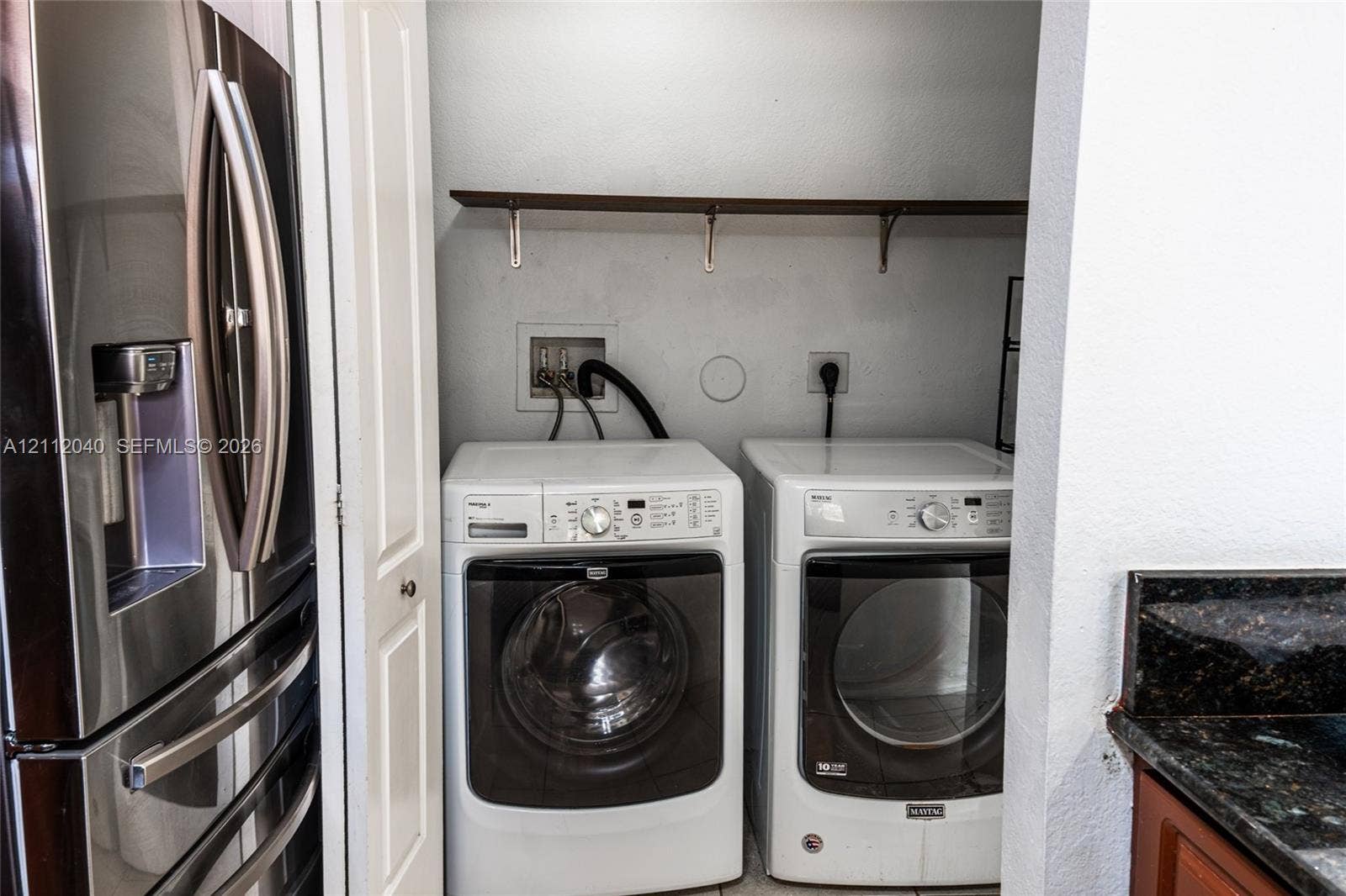 Laundry area featuring white front-loading appliances and a built-in wall-mounted shelving unit
