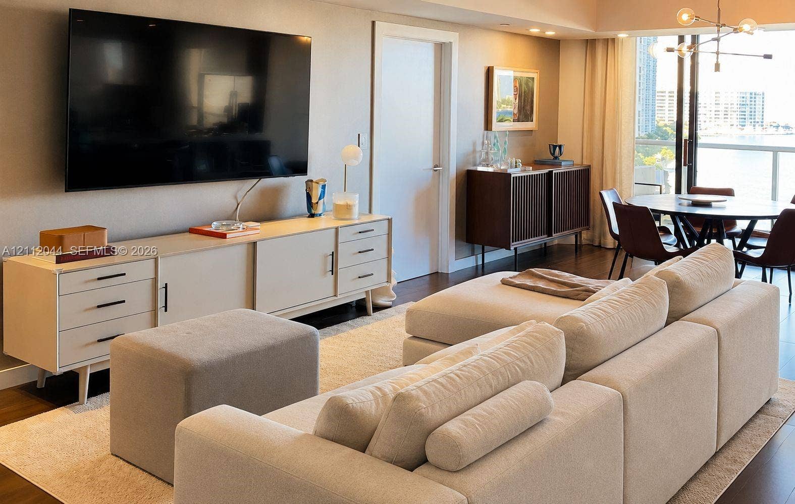 Living area featuring wood-finish flooring, recessed ceiling lighting, a swinging interior door, and a multi-bulb overhead light fixture