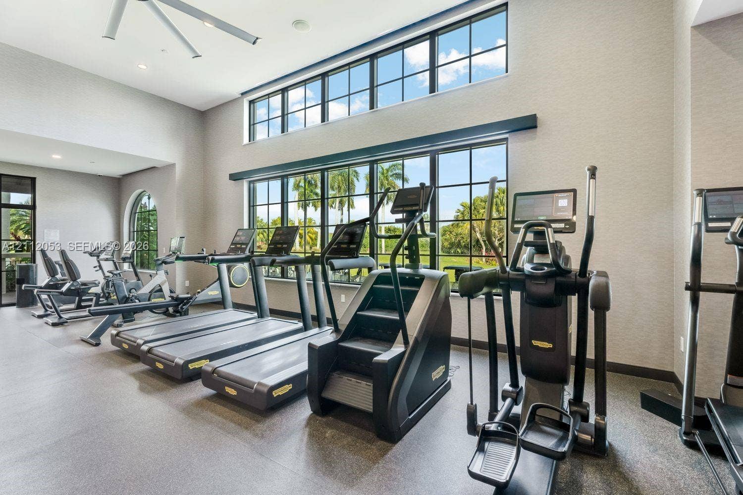 Fitness center featuring high ceilings, oversized black-framed windows, recessed lighting, and industrial-style ceiling fans