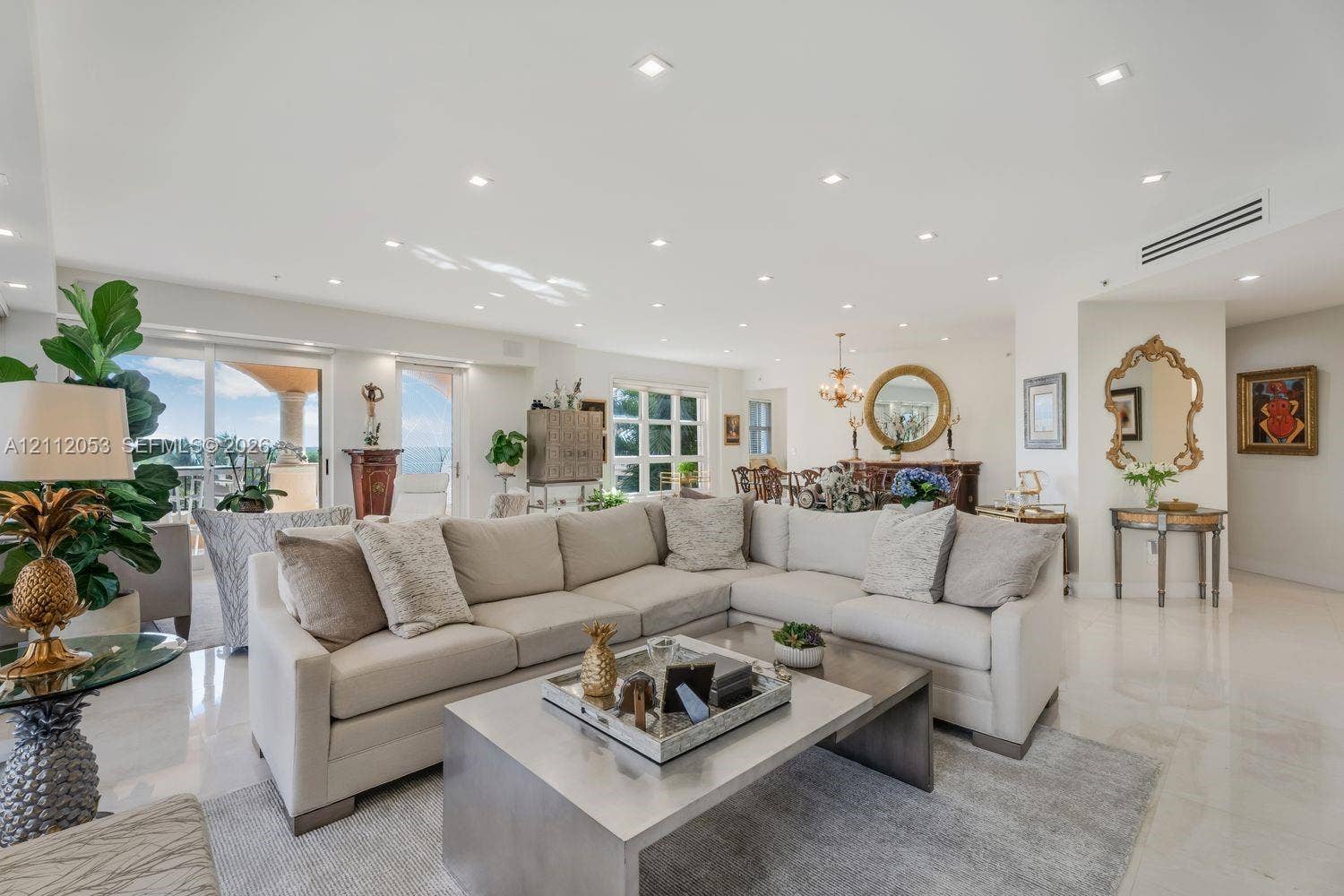 Open-concept living space featuring high ceilings, polished stone-finish flooring, recessed lighting, and expansive glass sliding doors