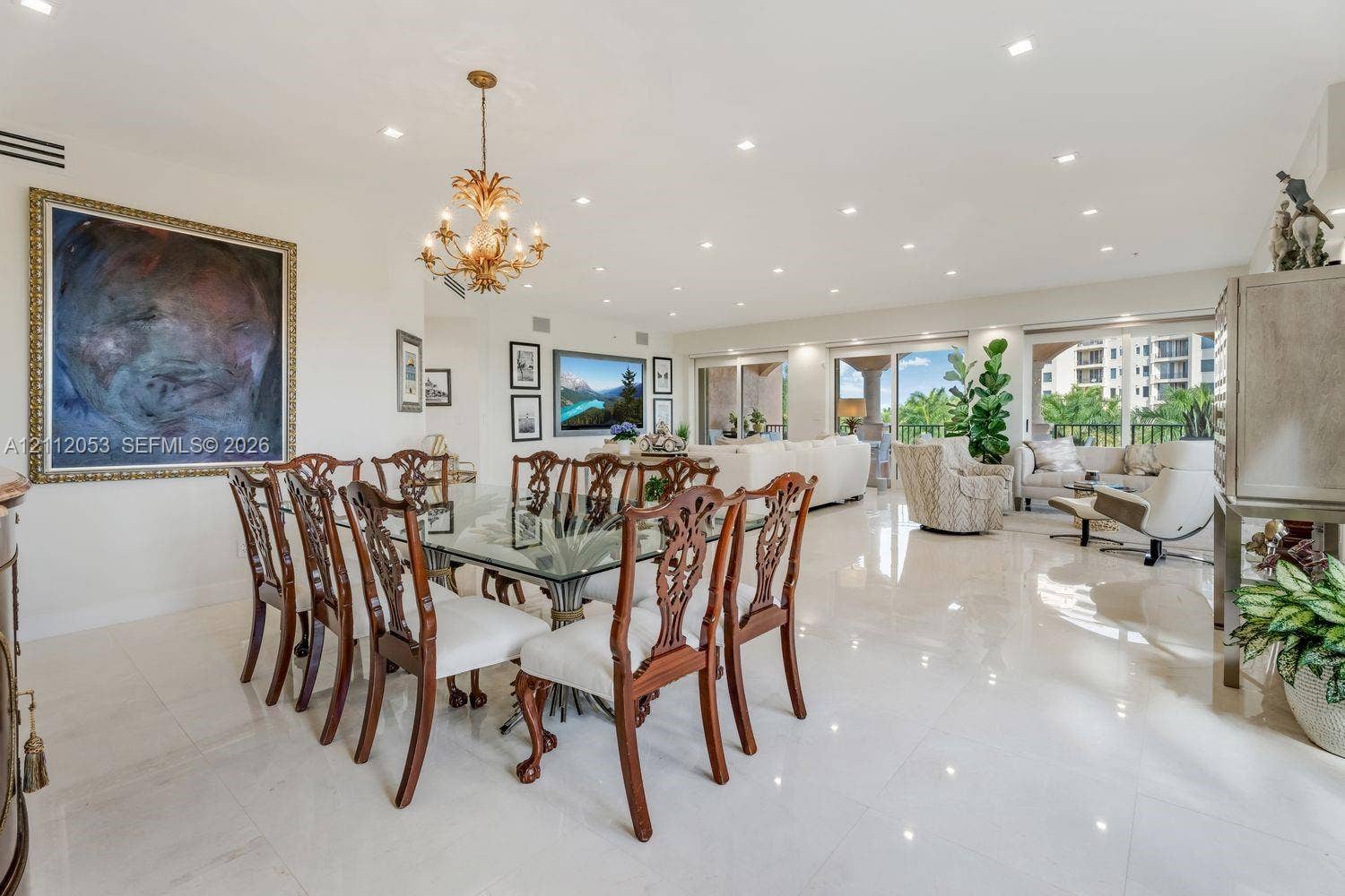 Open-concept interior featuring polished tile flooring, recessed ceiling lighting, a decorative metal chandelier, and floor-to-ceiling glass sliding doors