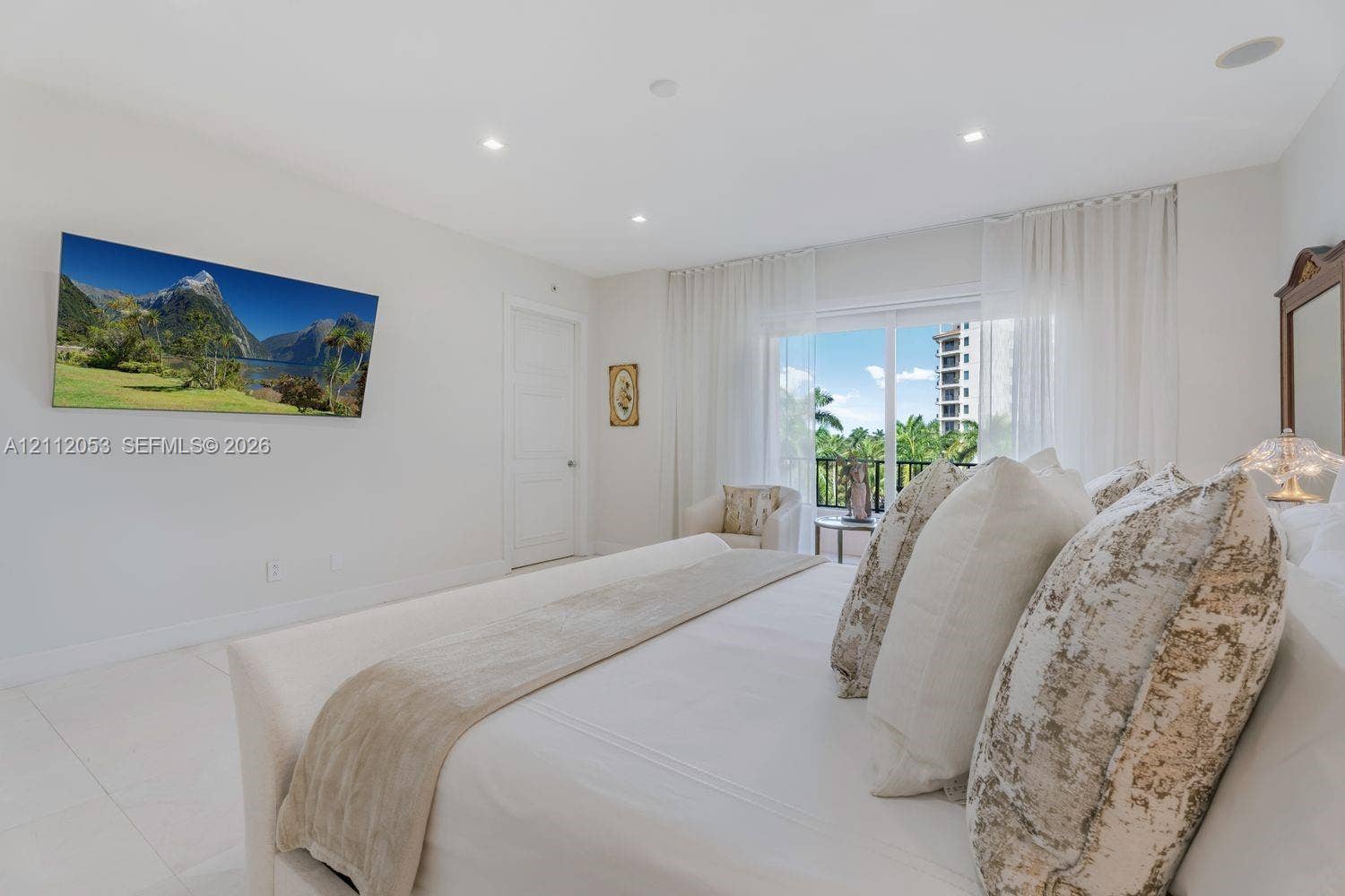 Light-filled room featuring white tile flooring, recessed lighting, and a sliding glass door providing access to a private balcony