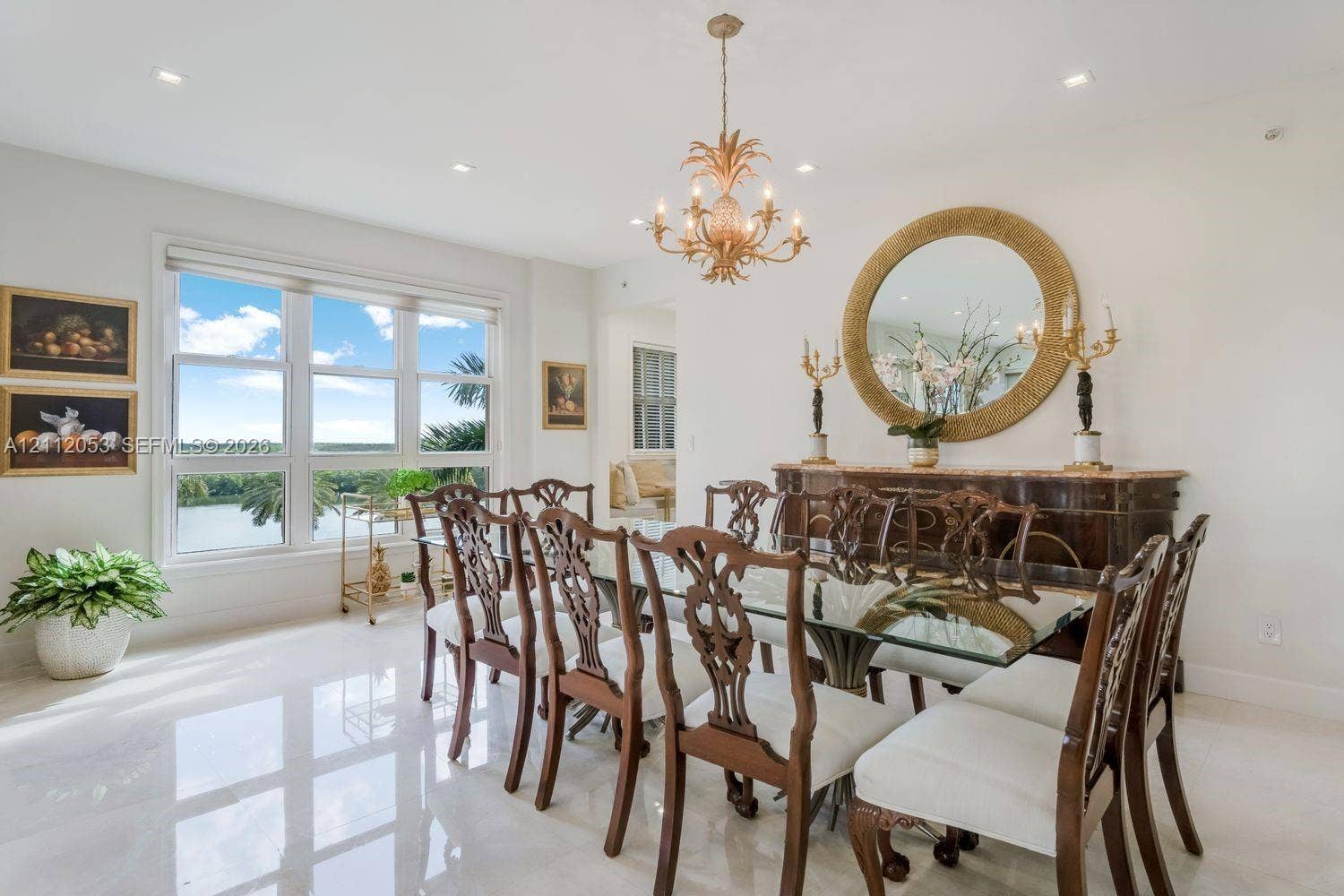 Dining area featuring polished stone flooring, large-scale multi-pane windows, recessed ceiling lighting, and a decorative gold-tone chandelier