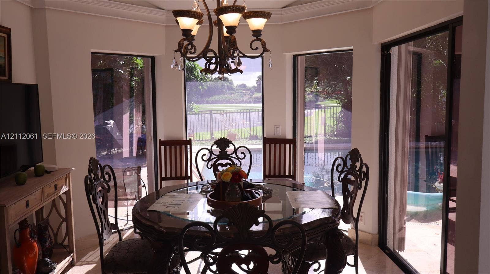 17191 SW Shaddock Lane, Boca Raton, FL 33487 Octagonal-shaped breakfast area featuring large floor-to-ceiling windows, crown molding, a multi-arm metal chandelier, and sliding glass doors leading to the exterior