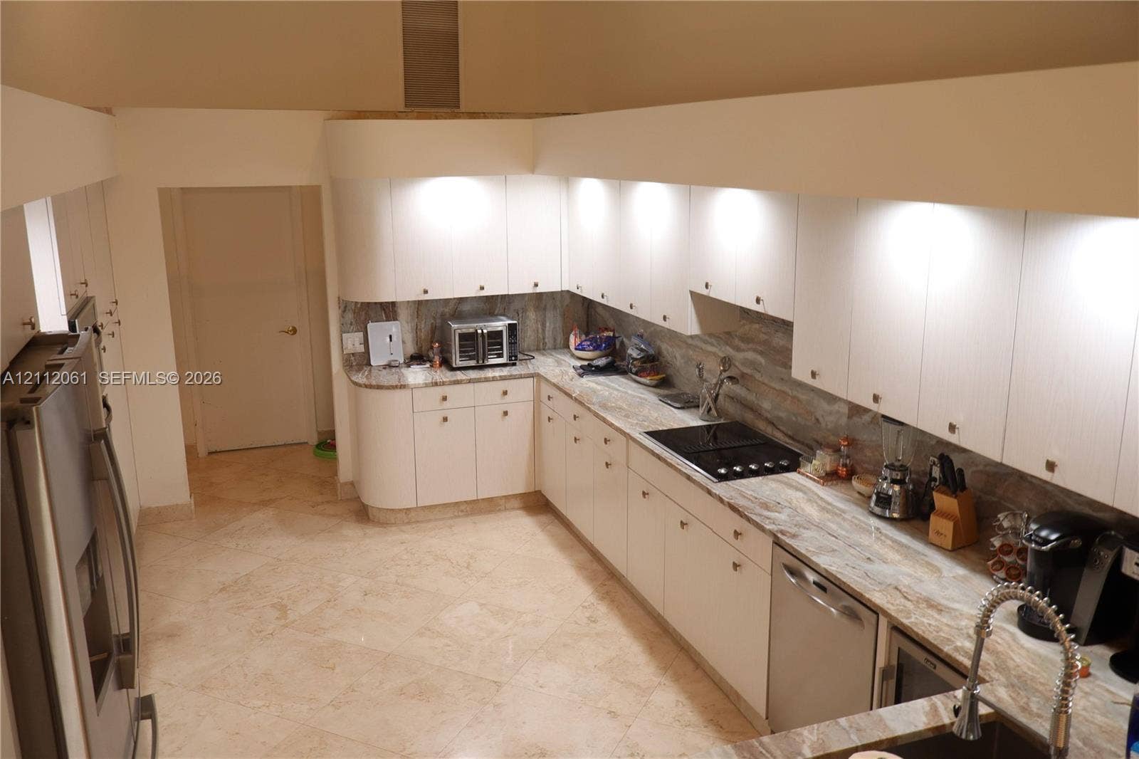 17191 SW Shaddock Lane, Boca Raton, FL 33487 Kitchen featuring light wood laminate cabinetry, pull out pantry ,solid marble countertops, matching marble backsplash, stainless steel appliances, and 24" marble flooring, dramatic high ceilings