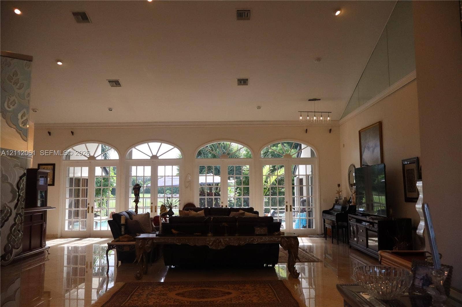 17191 SW Shaddock Lane, Boca Raton, FL 33487 High-ceiling interior featuring polished tile flooring, recessed lighting, and a series of four arched glass paneled double doors