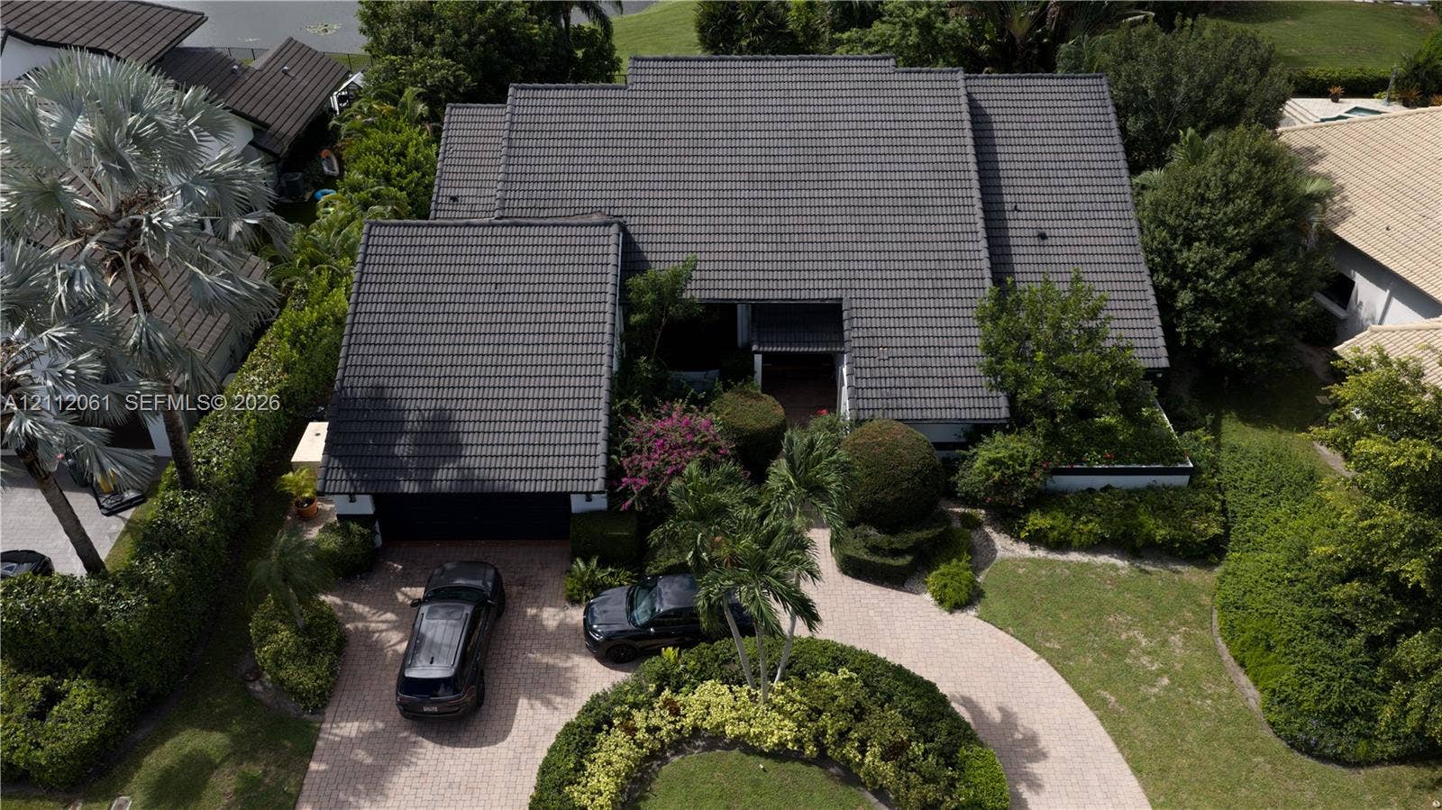 17191 SW Shaddock Lane, Boca Raton, FL 33487 Aerial perspective featuring a multi-gabled tiled roof, paver circular driveway, and mature landscaping