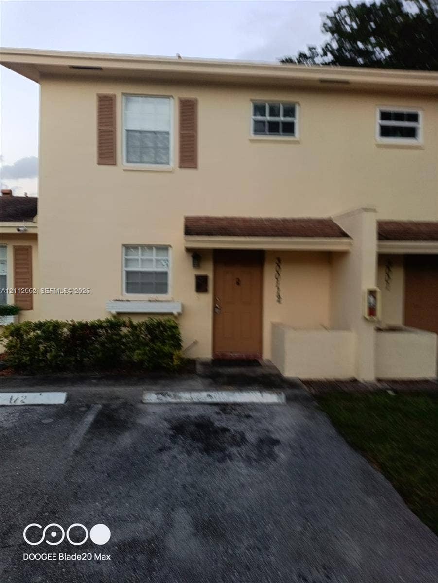 300112 NW 68th Street, #9G, Fort Lauderdale, Fort Lauderdale, FL 33309 Two-story exterior featuring light-toned stucco facade, decorative window shutters, a covered entryway, and designated off-street parking