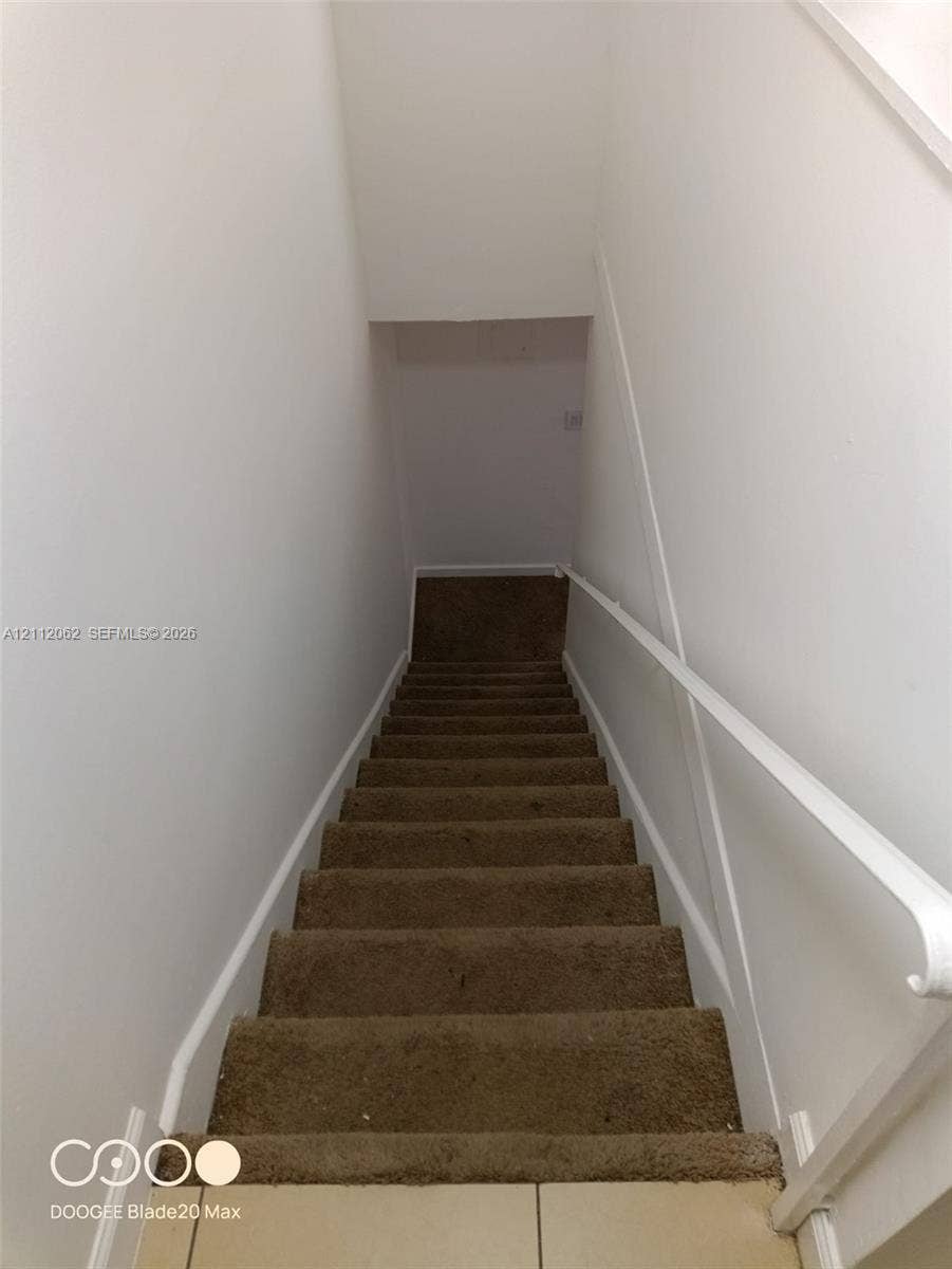 300112 NW 68th Street, #9G, Fort Lauderdale, Fort Lauderdale, FL 33309 Staircase featuring neutral-toned carpeting and a white wall-mounted handrail
