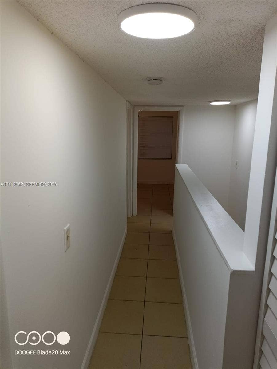 300112 NW 68th Street, #9G, Fort Lauderdale, Fort Lauderdale, FL 33309 Neutral interior hallway featuring tile flooring, ceiling-mounted disc lighting, and crisp white wall finishes