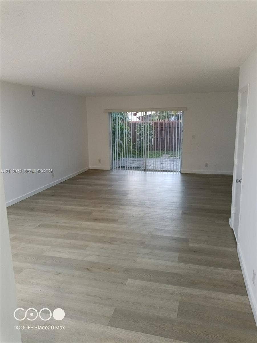300112 NW 68th Street, #9G, Fort Lauderdale, Fort Lauderdale, FL 33309 Open-concept interior featuring light-toned wood-finish flooring, neutral walls, and sliding glass doors with vertical blinds
