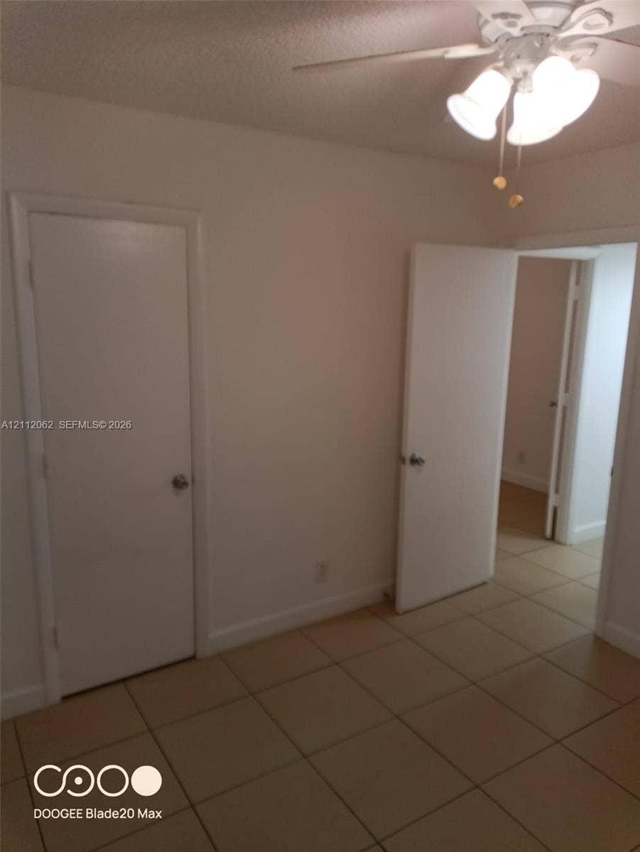 300112 NW 68th Street, #9G, Fort Lauderdale, Fort Lauderdale, FL 33309 Neutral-toned tile flooring, white-painted interior doors, and a ceiling-mounted light fixture with frosted glass shades