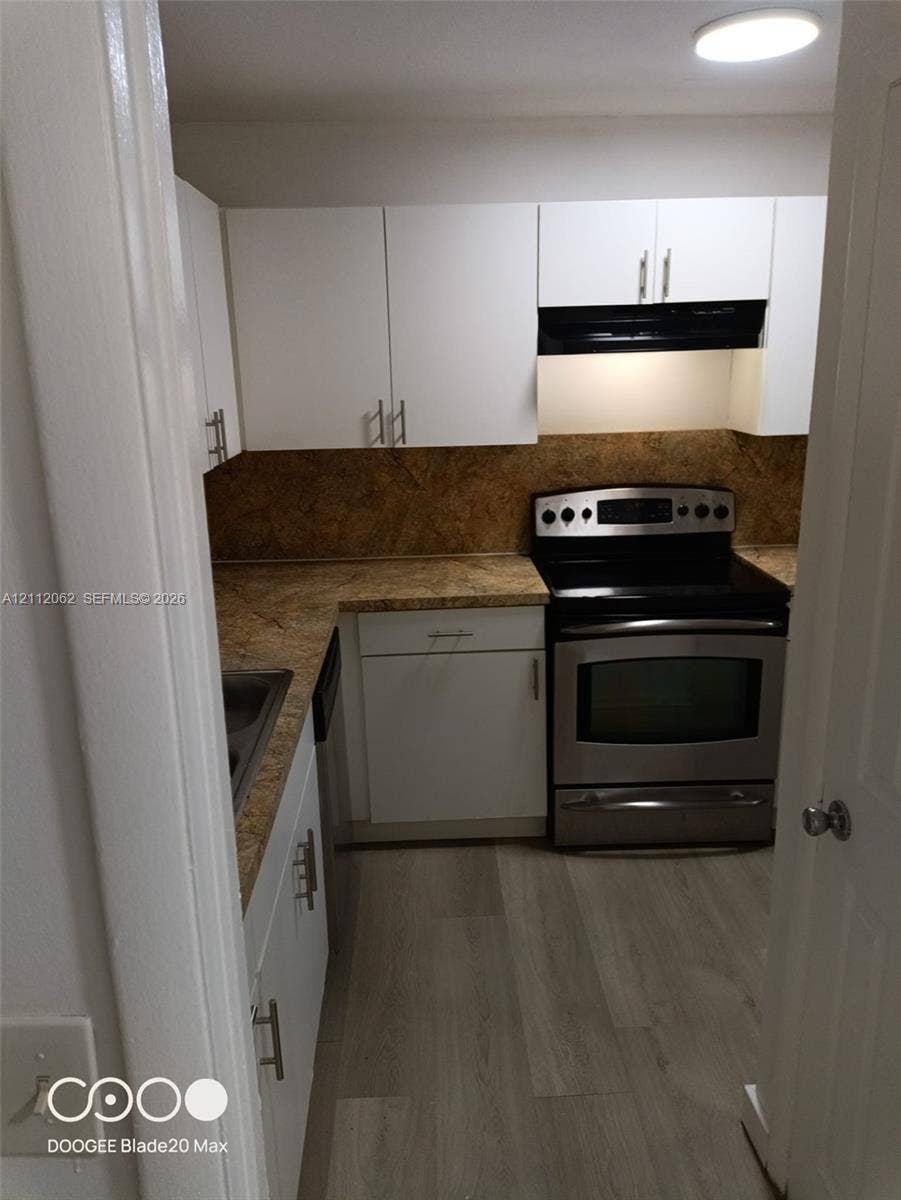 300112 NW 68th Street, #9G, Fort Lauderdale, Fort Lauderdale, FL 33309 Kitchen featuring white cabinetry with brushed-metal pulls, stone-patterned countertops, stone-patterned backsplash, stainless steel range, and wood-finish flooring
