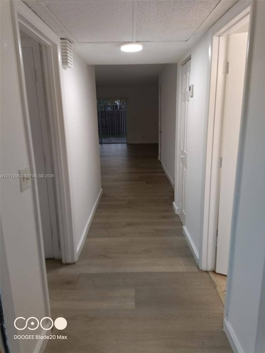 300112 NW 68th Street, #9G, Fort Lauderdale, Fort Lauderdale, FL 33309 Hallway featuring wood-finish flooring, white paneled interior doors, and a ceiling-mounted light fixture