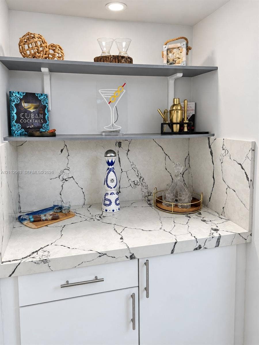 1360 S Ocean Boulevard, #2503, Pompano Beach, Pompano Beach, FL 33062 Built-in wet bar featuring stone-patterned surfacing, integrated backsplash, white cabinetry with metallic hardware, and dual grey floating shelves with recessed lighting