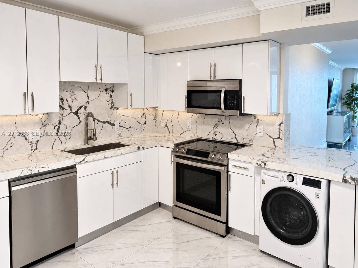 1360 S Ocean Boulevard, #2503, Pompano Beach, Pompano Beach, FL 33062 Kitchen featuring high-gloss white cabinetry, veined stone-finish countertops and backsplash, stainless steel appliances, and large-format tile flooring
