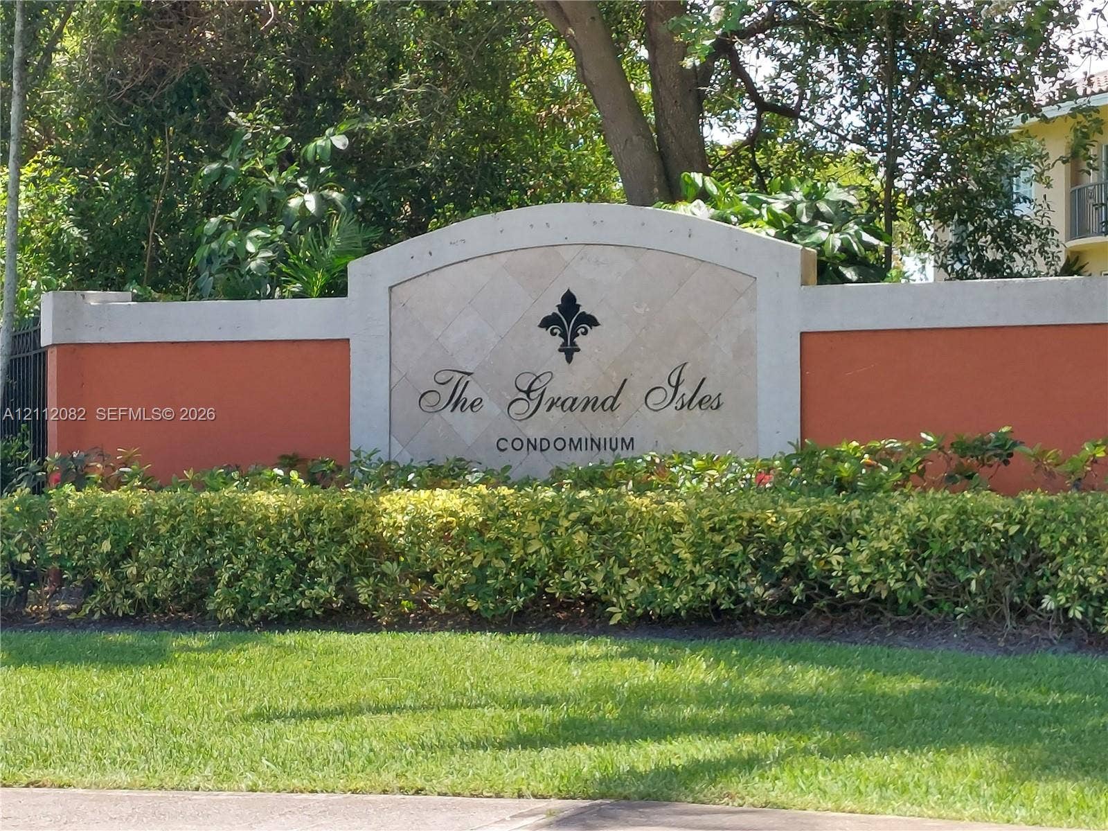 Community entrance monument featuring a stone-inlay center panel, arched concrete cap, and manicured landscaping