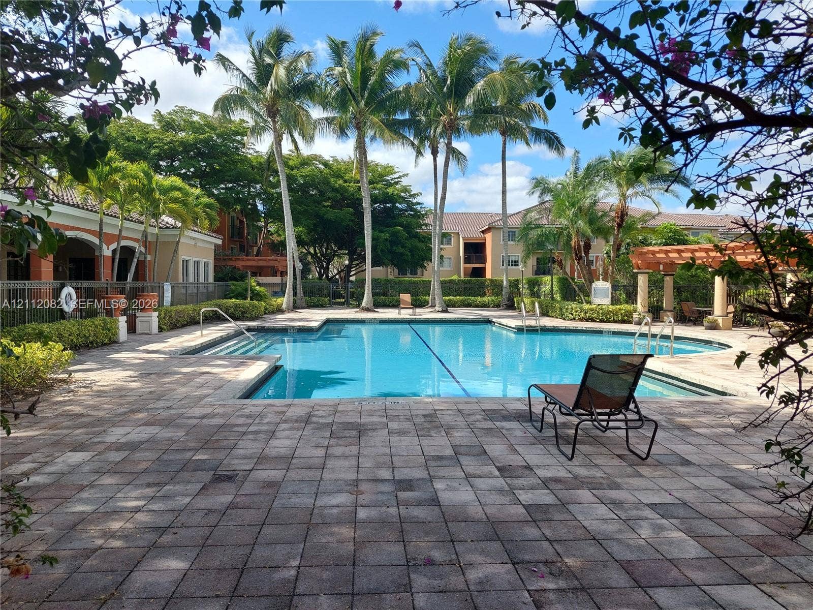 Swimming pool with entry steps, paved stone deck, and wood-finish pergola