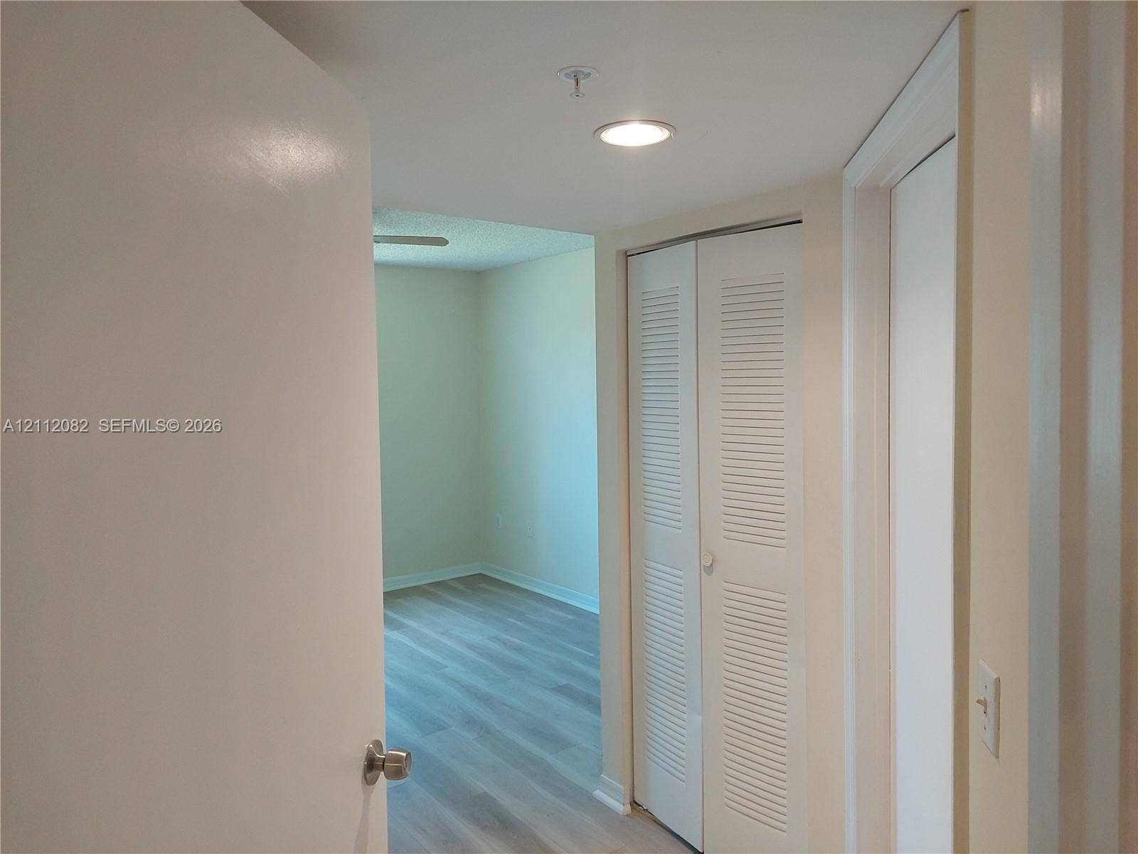 Hallway featuring wood-finish flooring, recessed lighting, and a white bifold louvered closet door