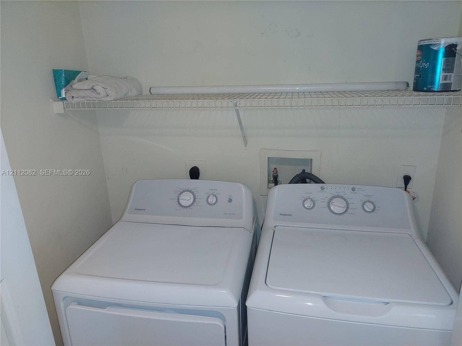 Laundry alcove featuring white top-loading appliances and an installed wire shelving unit