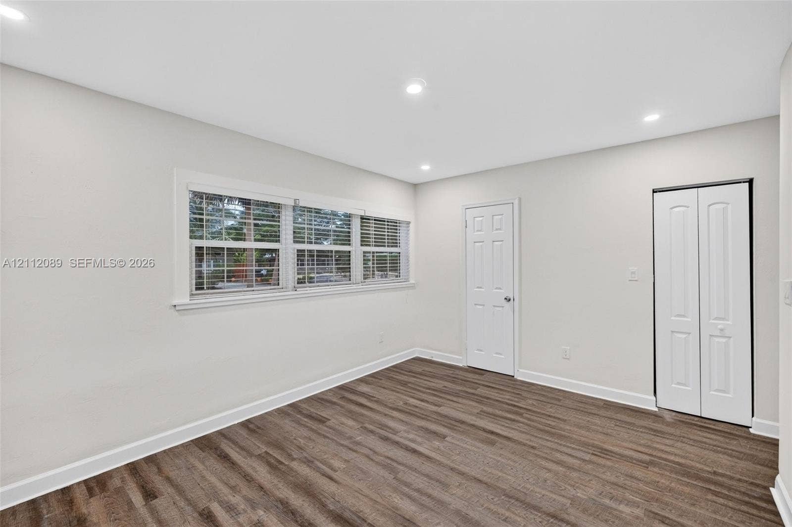 2017 NE 29th Court, Fort Lauderdale, FL 33306 Room featuring wood-finish flooring, recessed lighting, multi-pane windows with blinds, and a white six-panel closet door