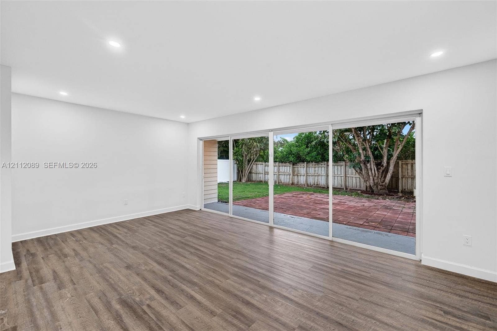 2017 NE 29th Court, Fort Lauderdale, FL 33306 Interior space featuring wood-finish flooring, recessed lighting, and expansive multi-panel sliding glass doors opening to a paved patio and fenced yard