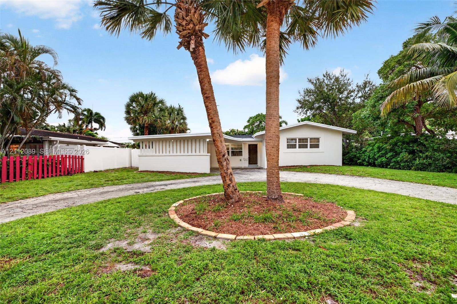 2017 NE 29th Court, Fort Lauderdale, FL 33306 Single-story exterior featuring white stucco siding, a curved driveway, and a decorative slatted privacy screen
