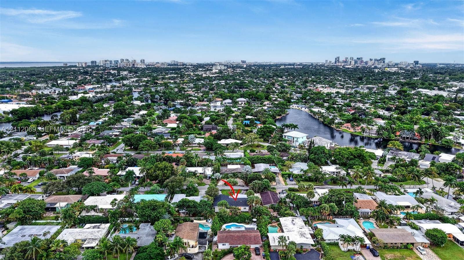 2017 NE 29th Court, Fort Lauderdale, FL 33306 Aerial perspective showcasing a residential property with a detached garage and a swimming pool, situated within a coastal landscape featuring mature trees and proximity to a waterway and urban skyline