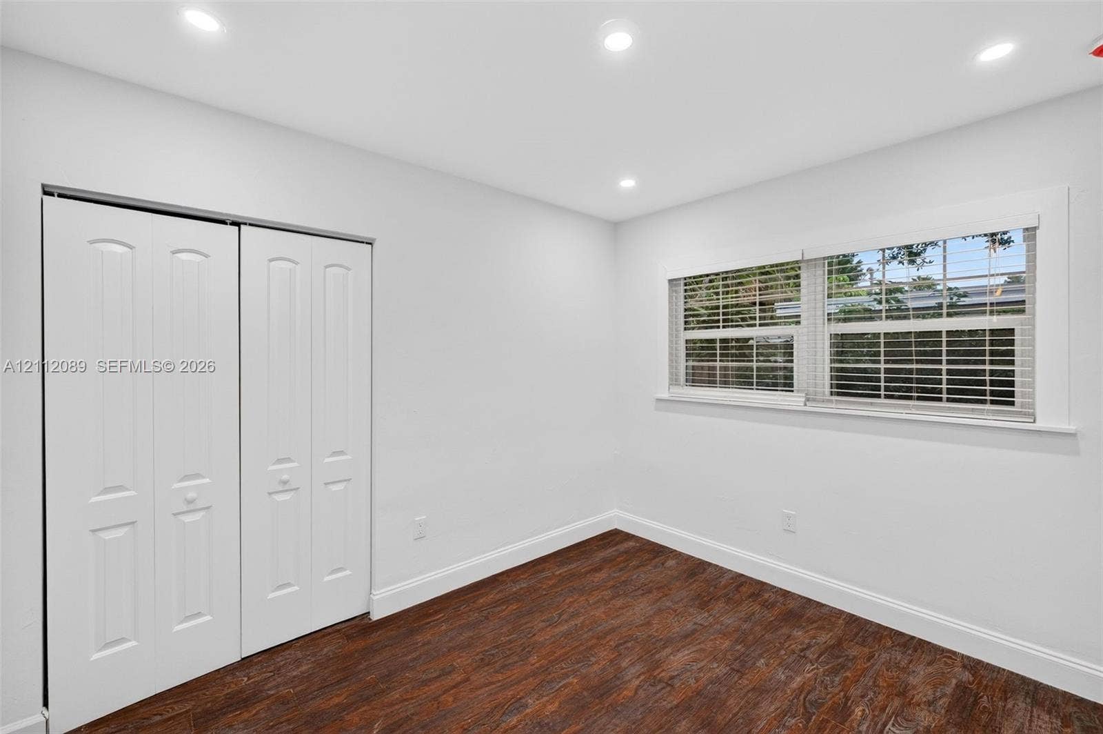 2017 NE 29th Court, Fort Lauderdale, FL 33306 Interior room featuring dark wood-finish flooring, recessed ceiling lighting, a large window with horizontal blinds, and a double-panel closet with raised-panel doors