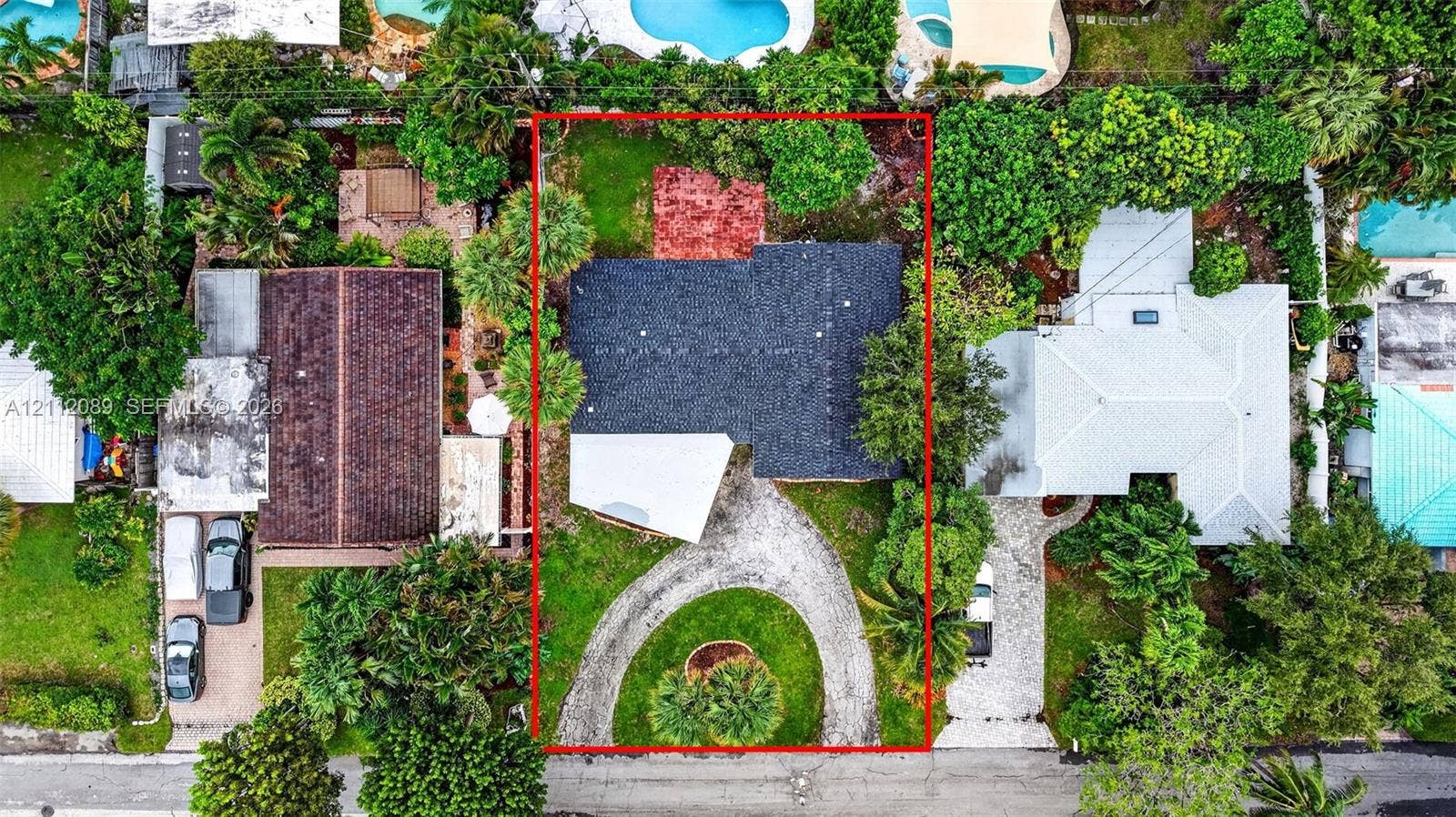 2017 NE 29th Court, Fort Lauderdale, FL 33306 Aerial perspective of property featuring a dark-toned shingle roof, a circular driveway, mature perimeter landscaping, and a rear stone-paved patio