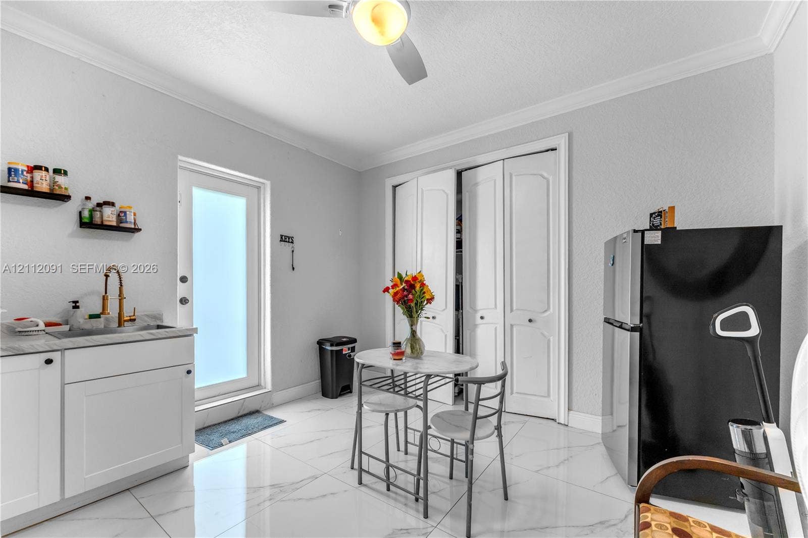 29481 SW 193rd Court, Homestead, FL 33030 Polished tile flooring, built-in lower cabinetry with stone-finish countertops, undermount sink with brass-finish faucet, bi-fold closet doors, and exterior door with frosted glass insert