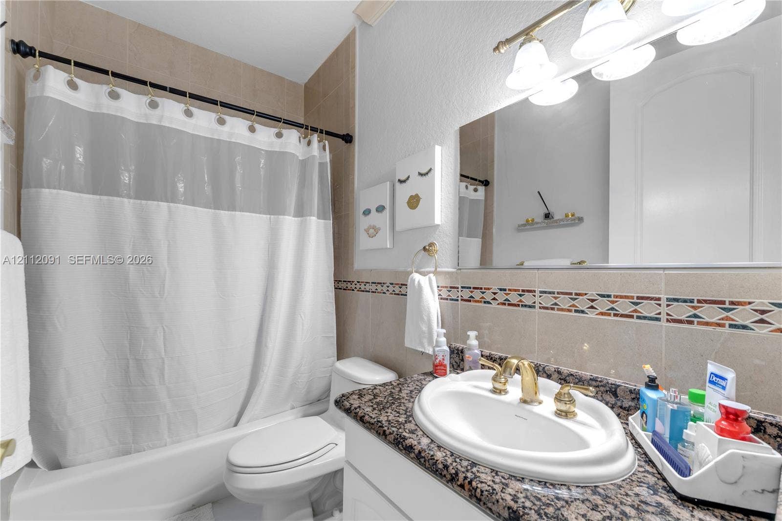 29481 SW 193rd Court, Homestead, FL 33030 Bathroom featuring a stone-surface vanity countertop, drop-in sink with brass-toned hardware, decorative tile backsplash, and a tub-shower combination with full-height tile wall surround